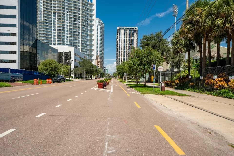 Two-way protected bike lane on wide street in downtown St. Petersburg, Florida with high-riise buildings in background.